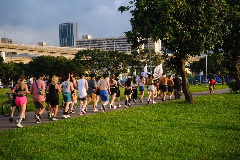 A group of runners on a riverside path lined with trees.